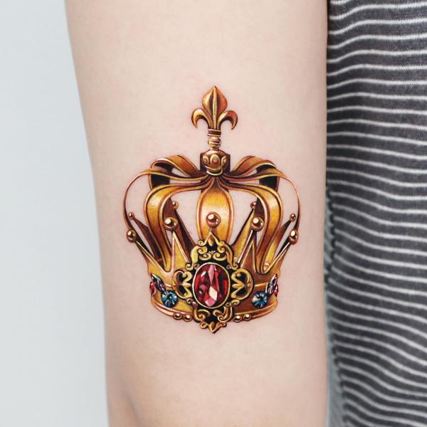 Gold Crown back of arm tattoo