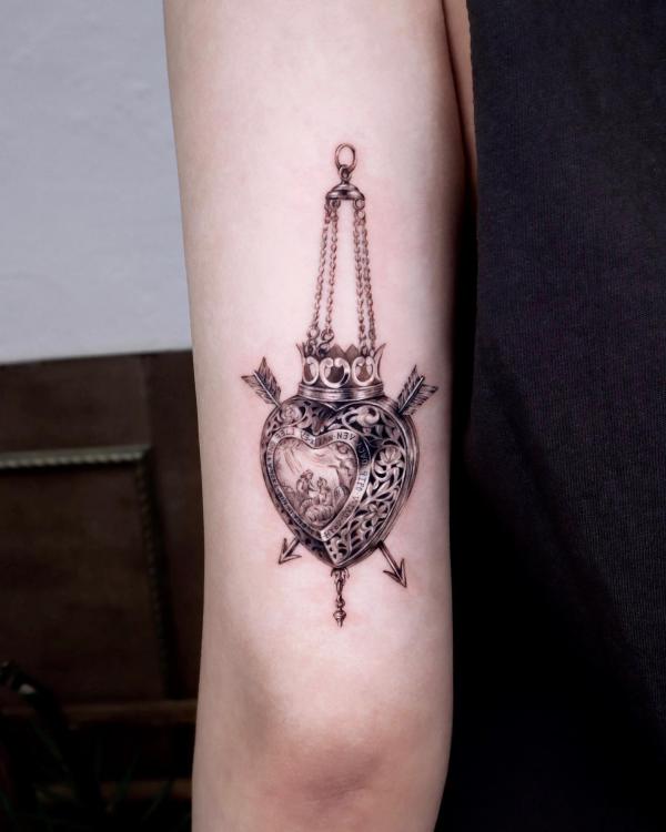 Metallic sacred heart with arrows back of arm tattoo