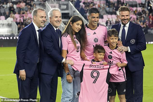 Inter Miami co-owner David Beckham, right, poses with Inter Miami forward Luis Suarez, second from right at rear, and his family before the team's MLS soccer match against Real Salt Lake, Wednesday, Feb. 21, 2024, in Fort Lauderdale, Fla. At left is Inter Miami co-owner Jose Mas, and second from left is manager owner Jorge Mas. (AP Photo/Lynne Sladky)