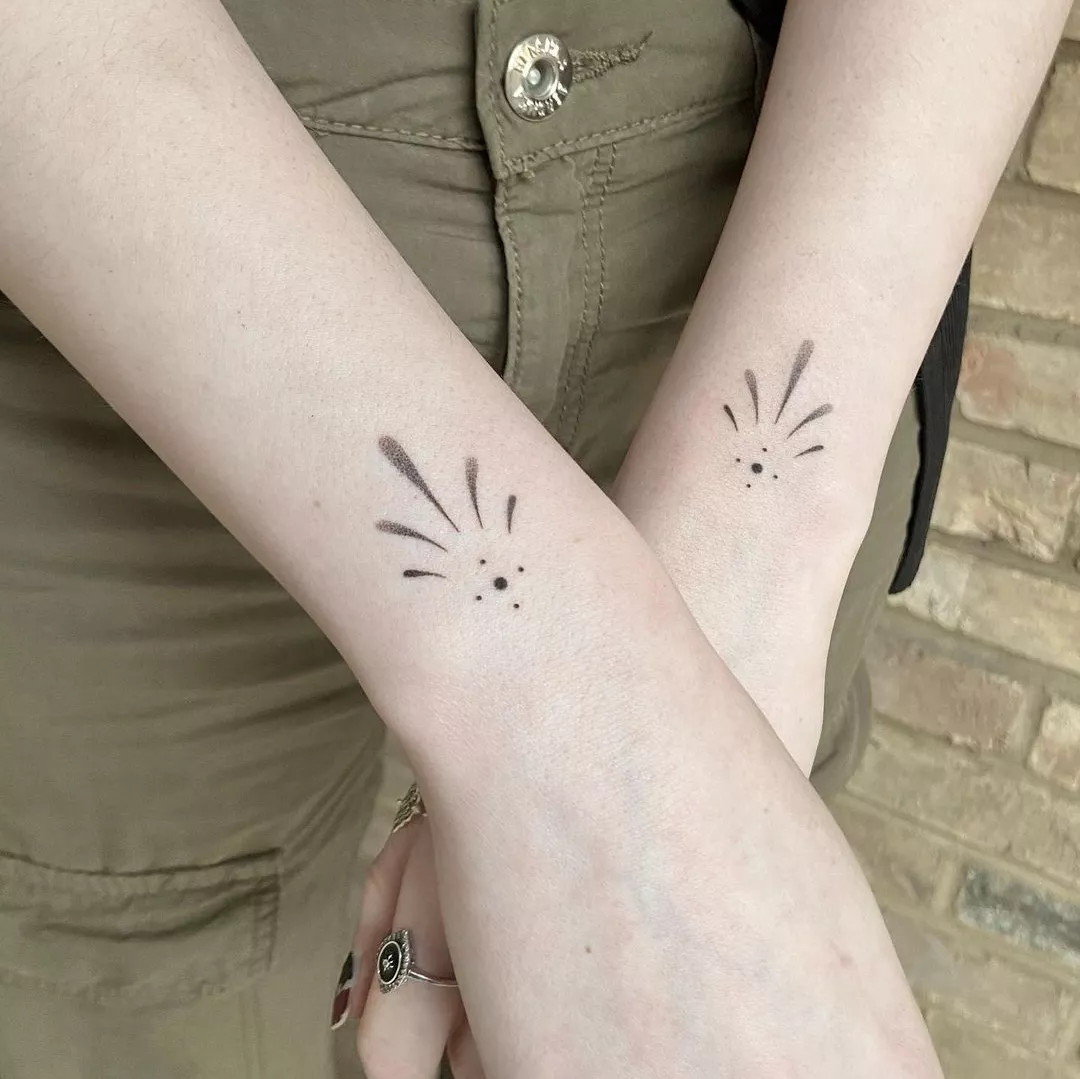 woman's wrists with black tattoos on top of each