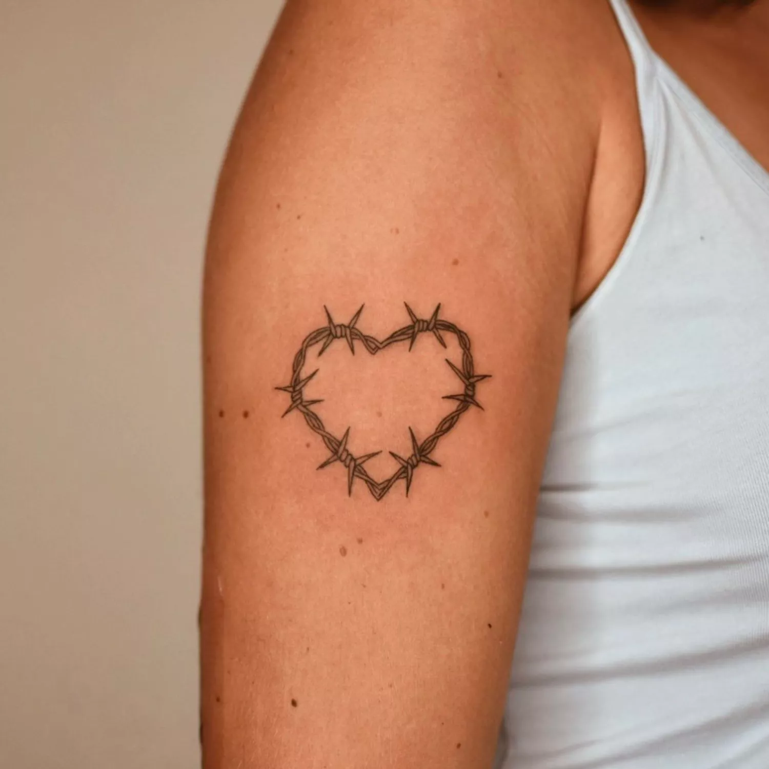 A barbed-wire heart tattoo on the mid-arm.