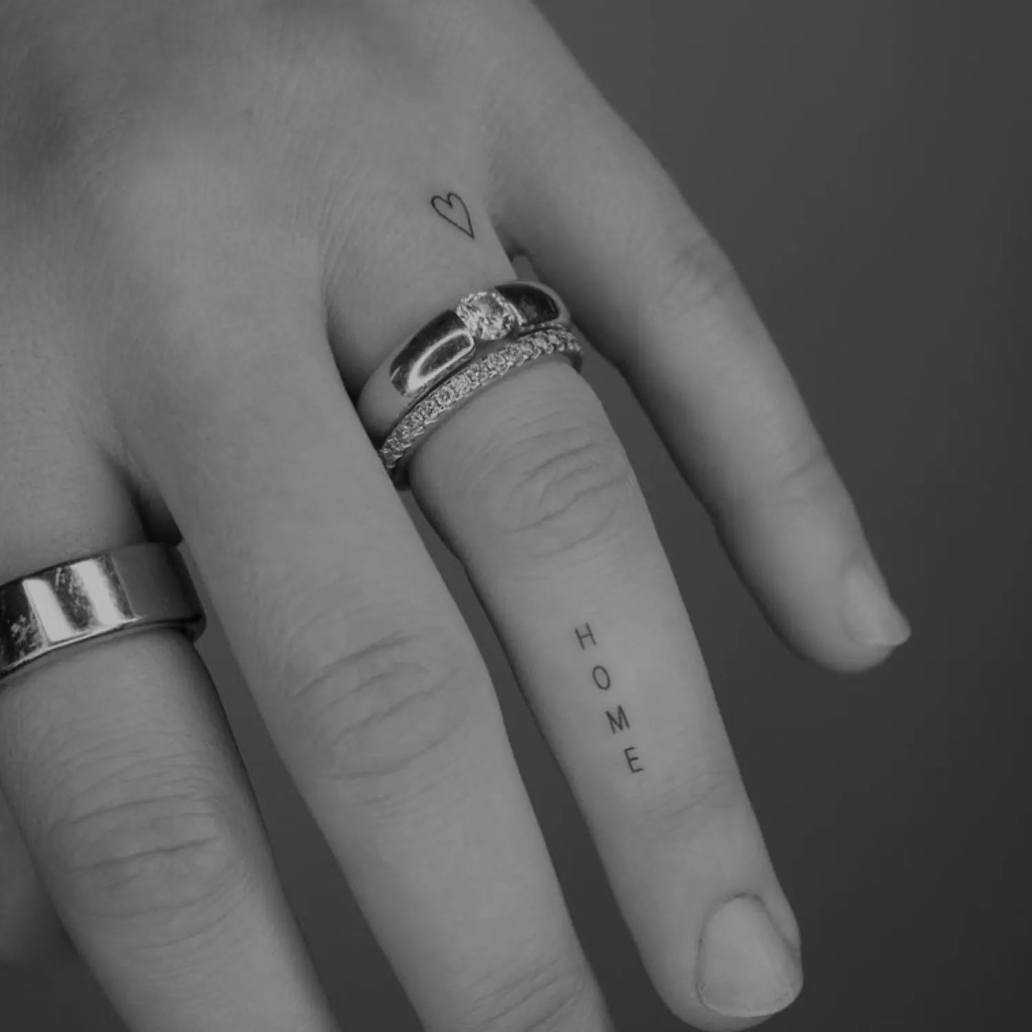 A tiny heart tattoo on the top part of the ring finger.