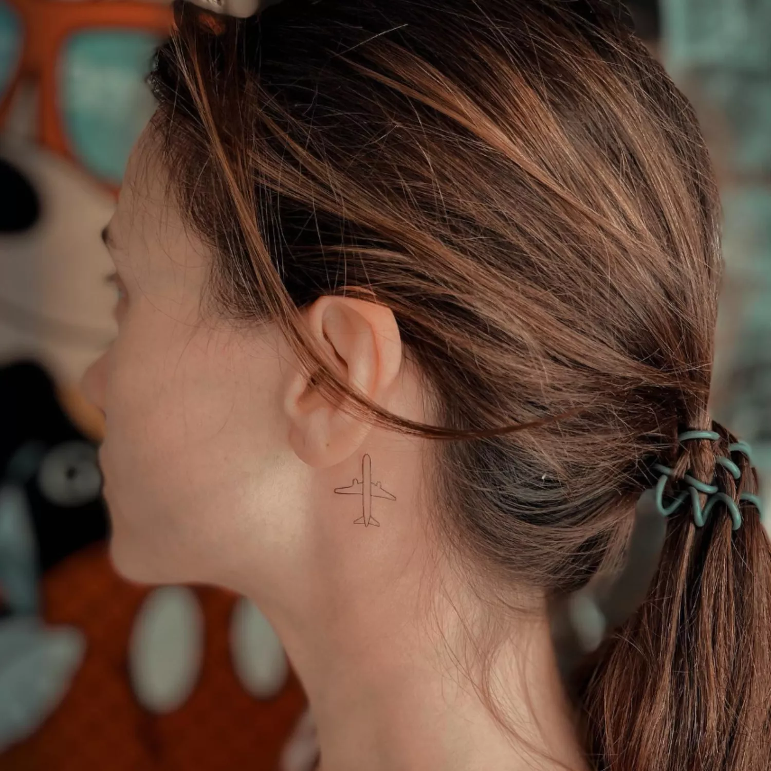zoomed-in photo of person with airplane tattoo behind the ear