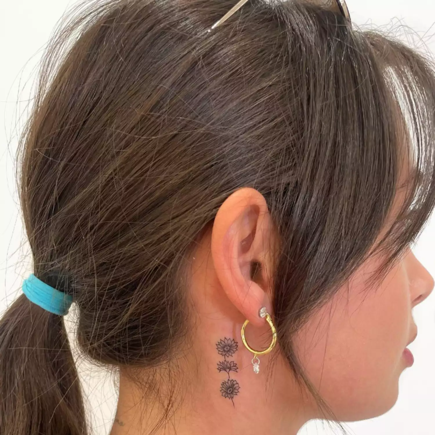 zoomed-in photo of person with flower tattoo behind the ear