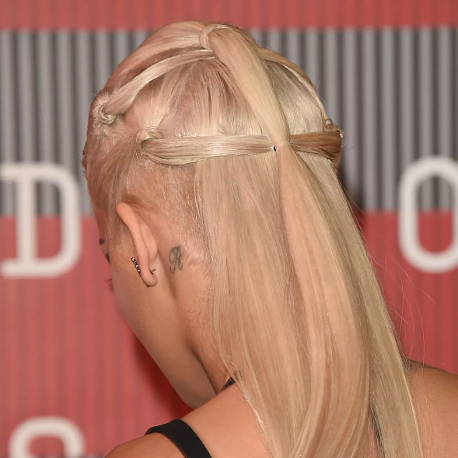 zoomed-in photo of Rita Ora with r initial tattoo behind the ear