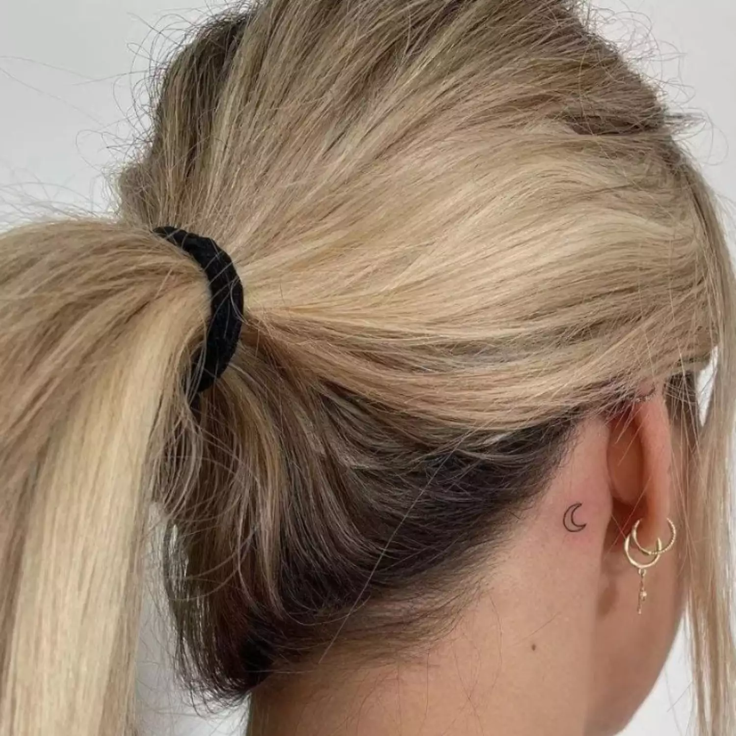 zoomed-in photo of person with moon tattoo behind the ear