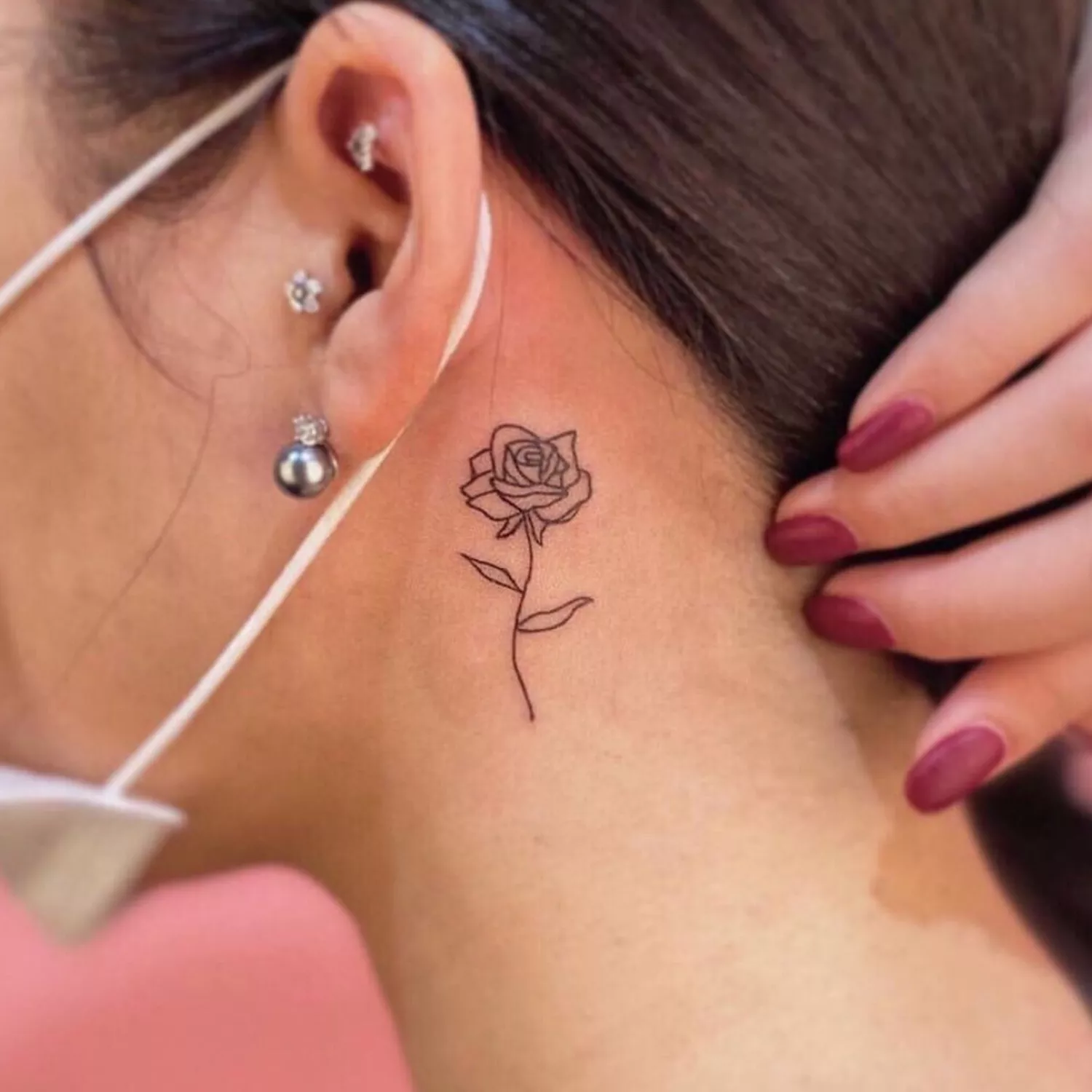 zoomed-in photo of person with rose tattoo behind their ear