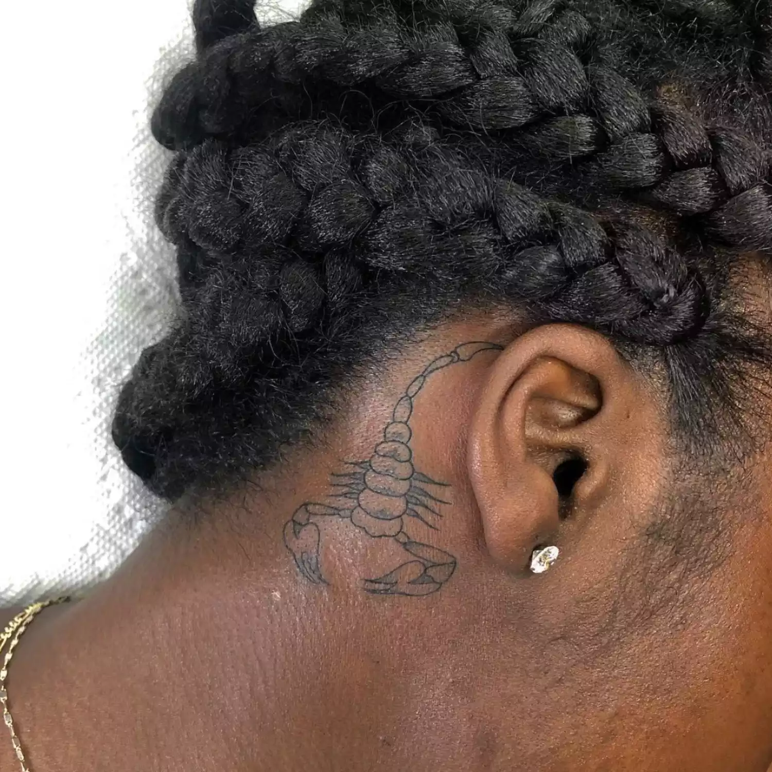 zoomed-in photo of person with scorpion tattoo behind the ear