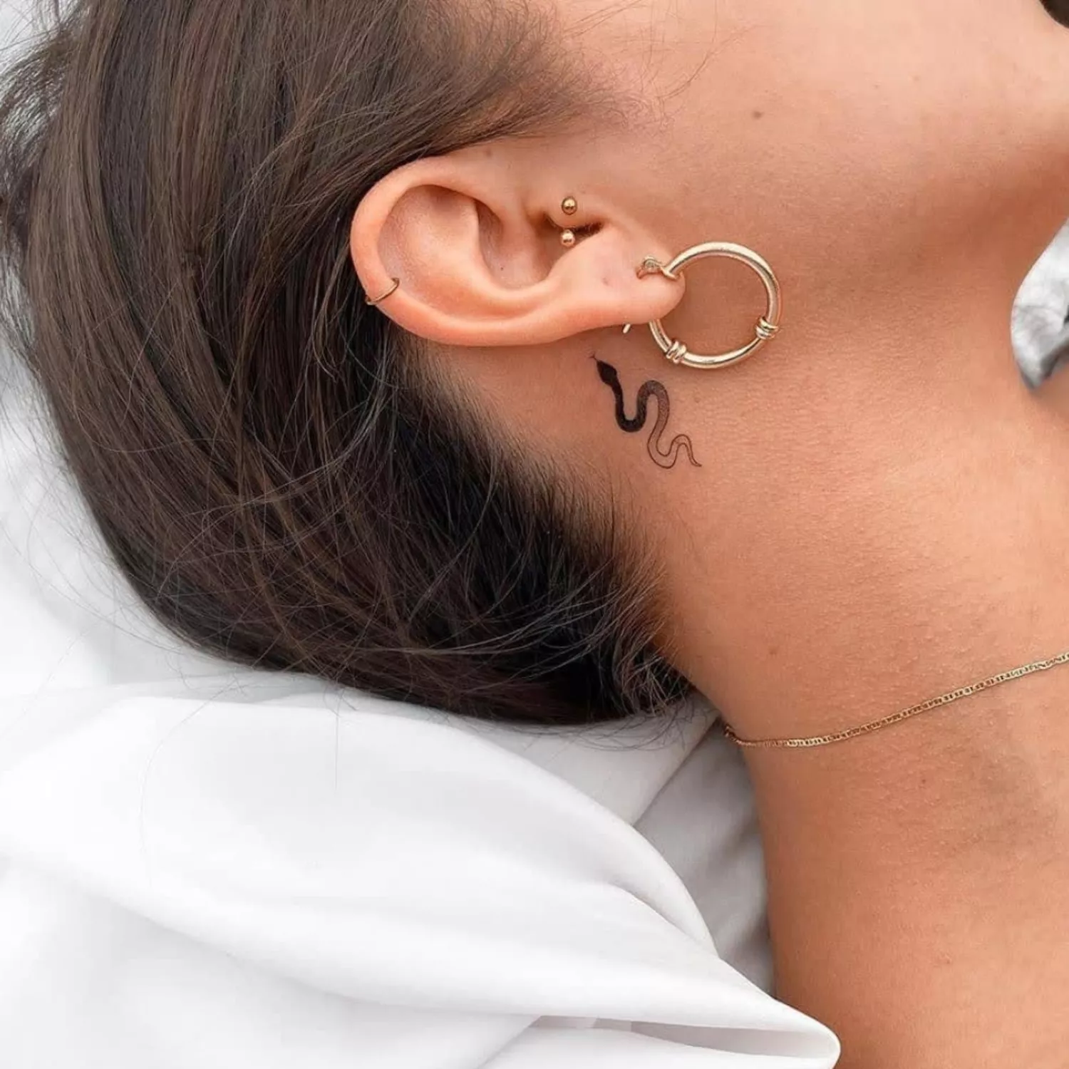 zoomed-in photo of person with snake tattoo behind the ear