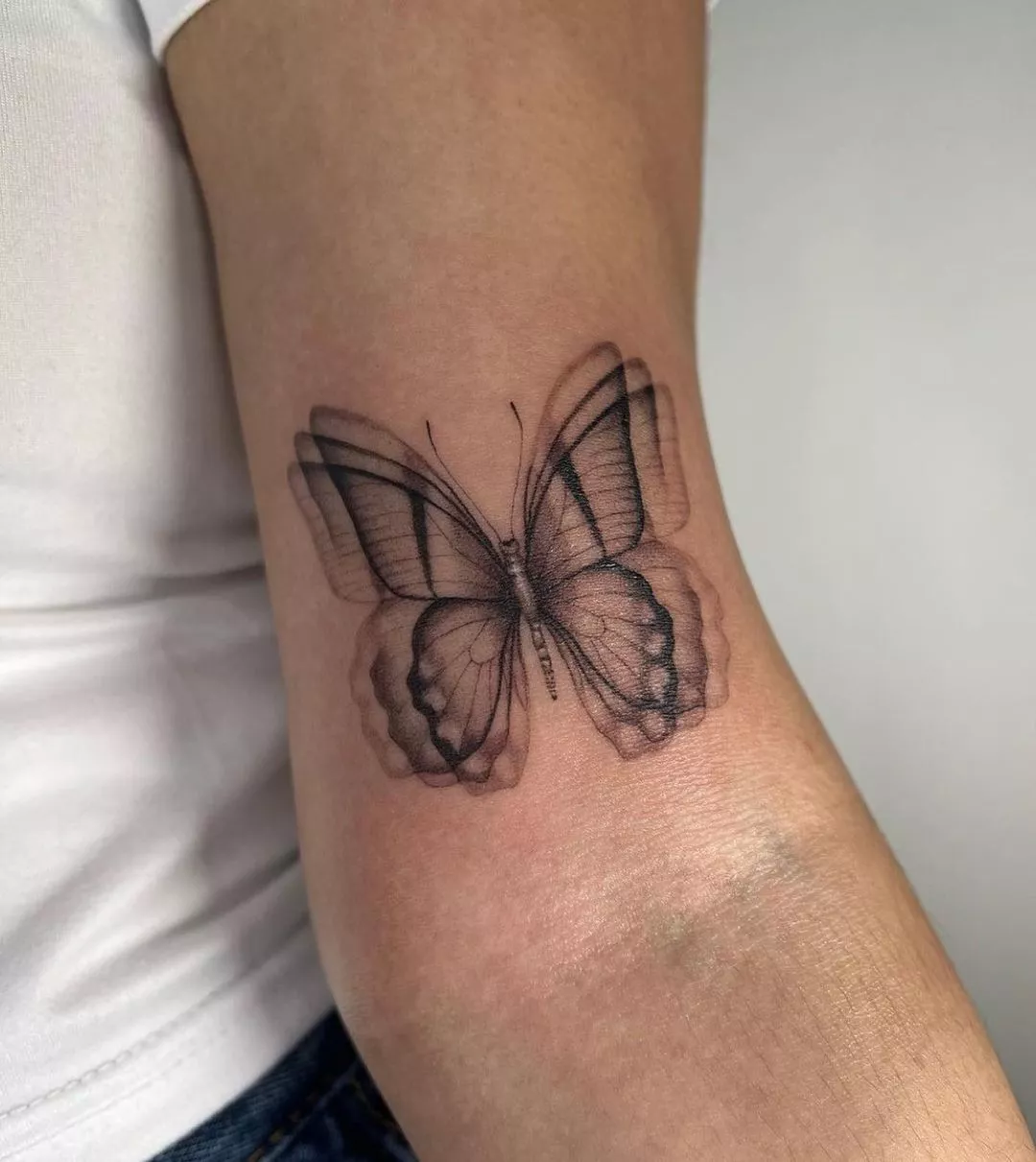 Close up of an arm with a butterfly tattoo that looks like the wings are flapping