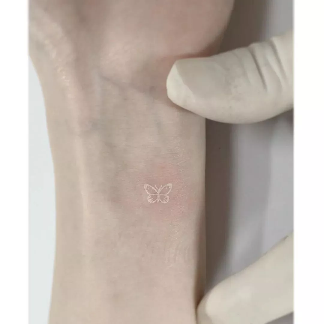 Close up of a tiny white butterfly tattoo on the wrist