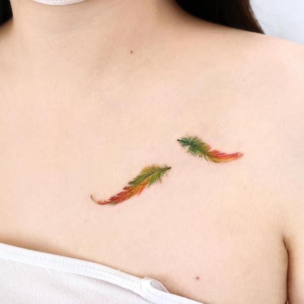 Small green and orange feather tattoo by @palette.tt