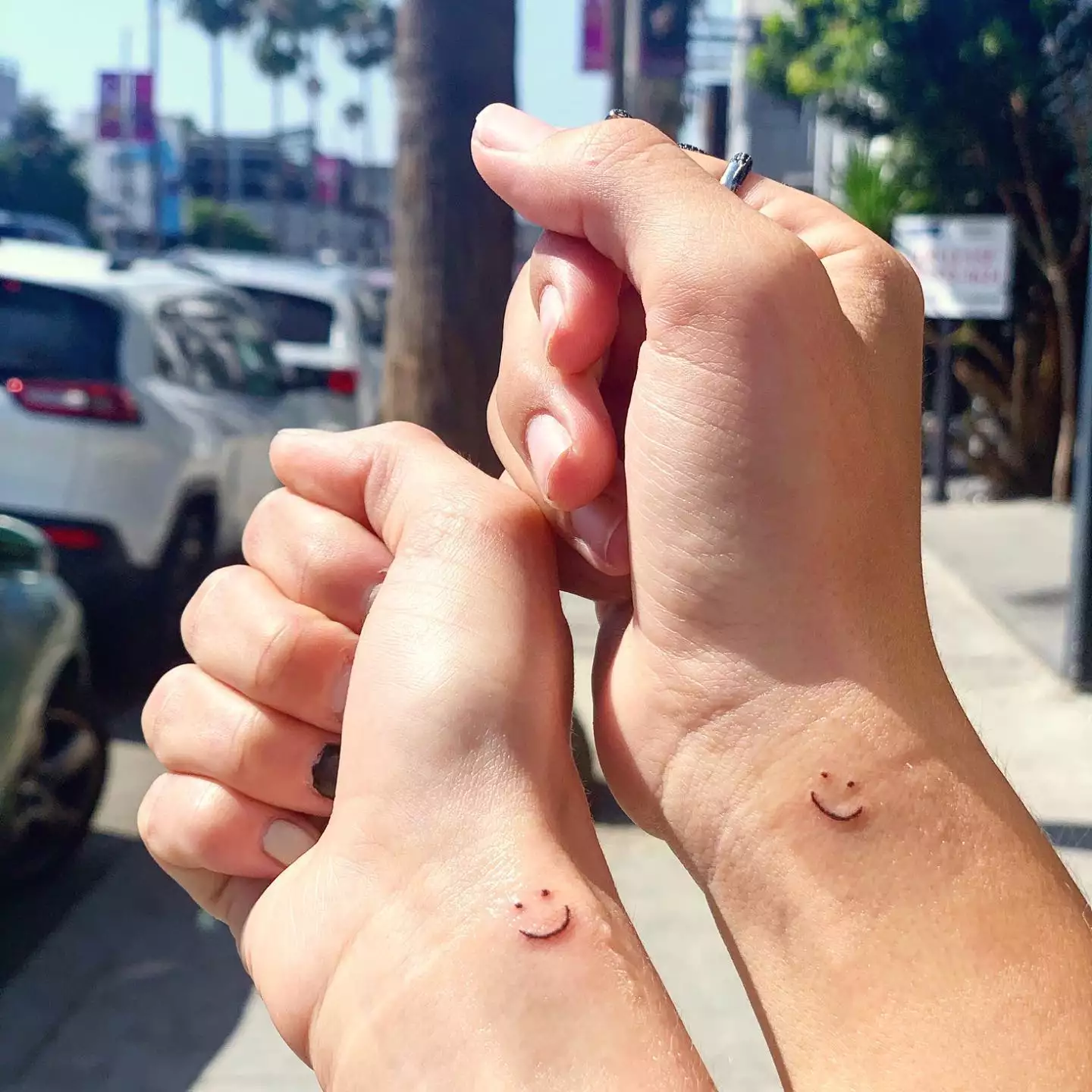 matching smiley face tattoos on two wrists