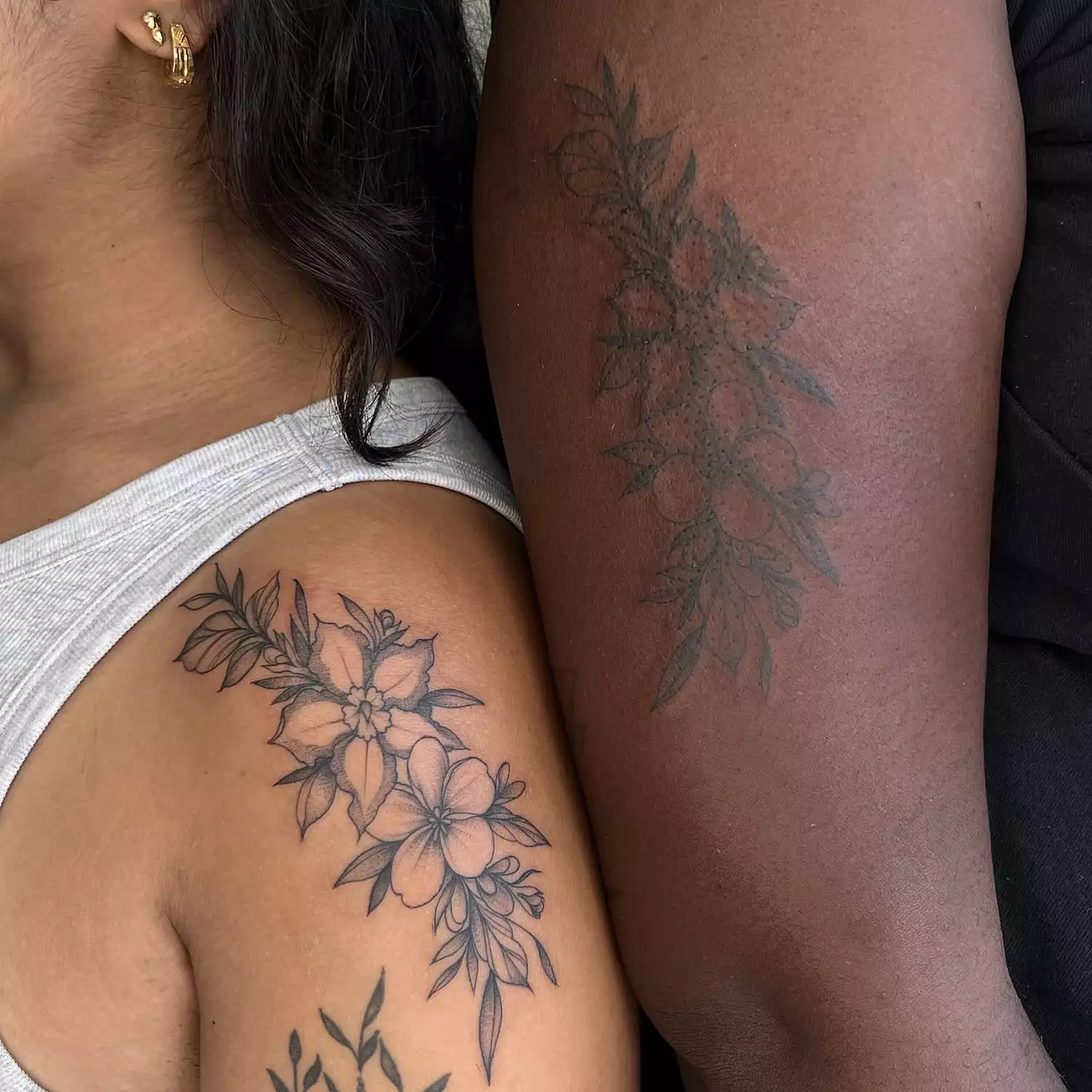 BFFs with matching floral swag tattoos on upper arms