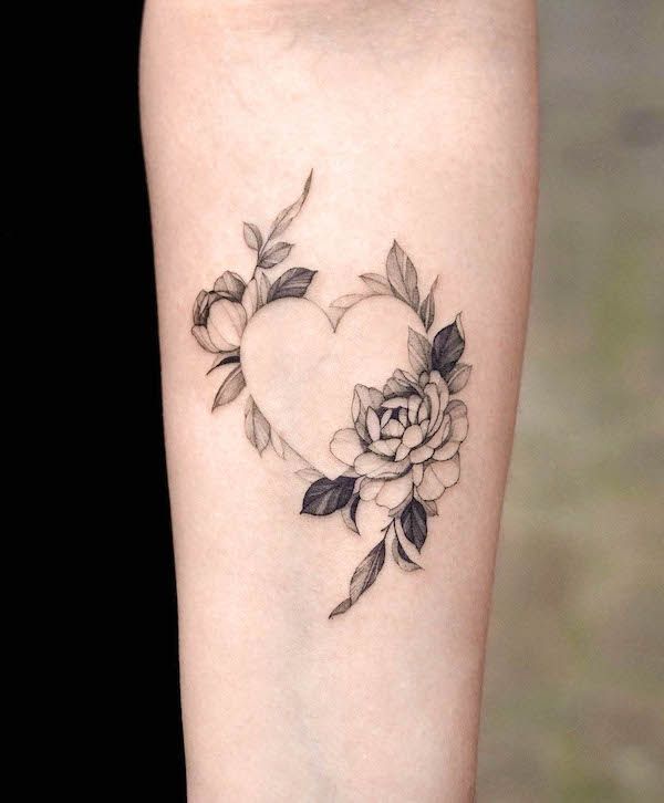 This may contain: a heart shaped tattoo with flowers and leaves on the side of the leg, in black ink