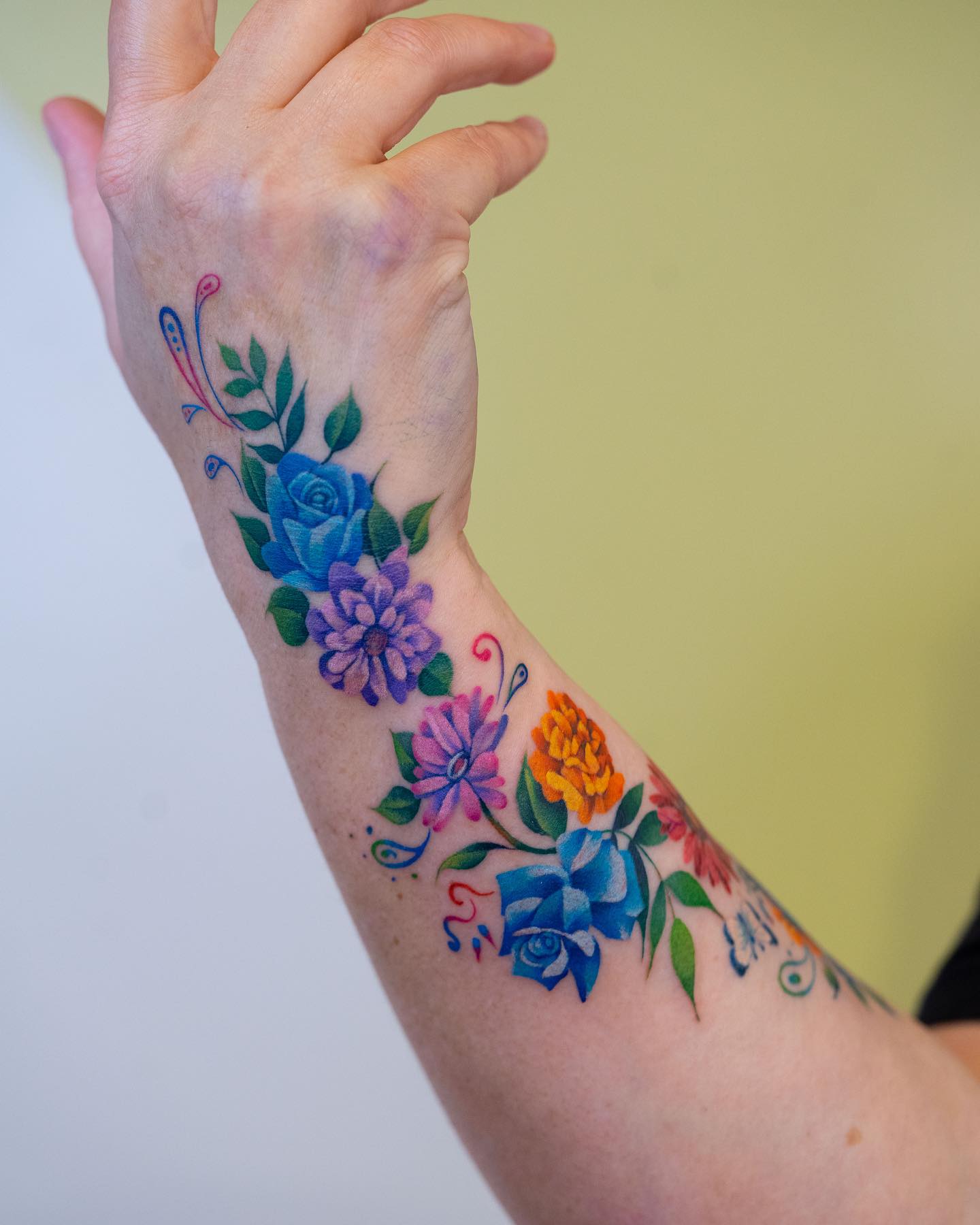 Colorful floral composition tattooed on the wrist and forearm