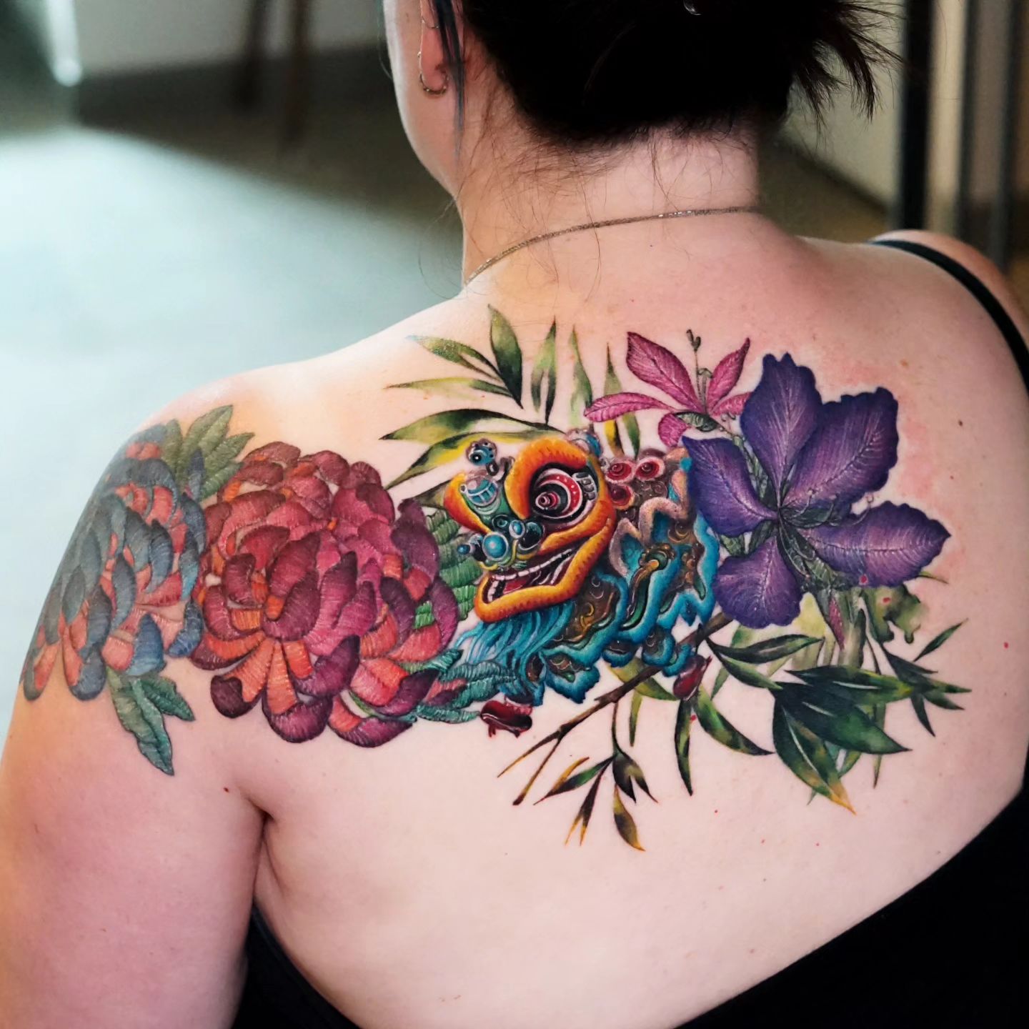 Colorful floral composition tattooed on the upper back