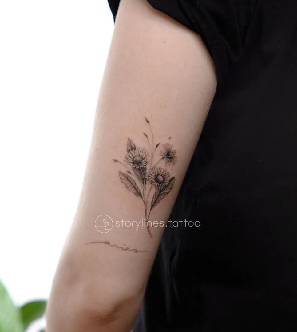 Daisy bouquet tattooed on the outer arm