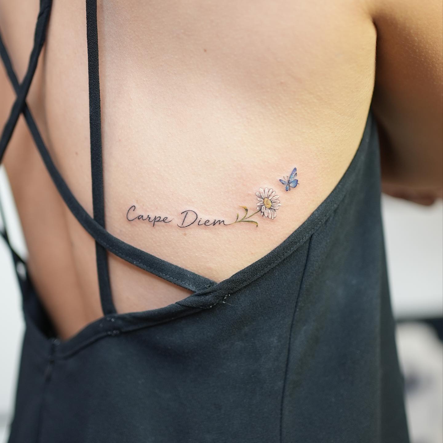 "Carpe diem", daisy flower, and blue butterfly tattoo located on the back