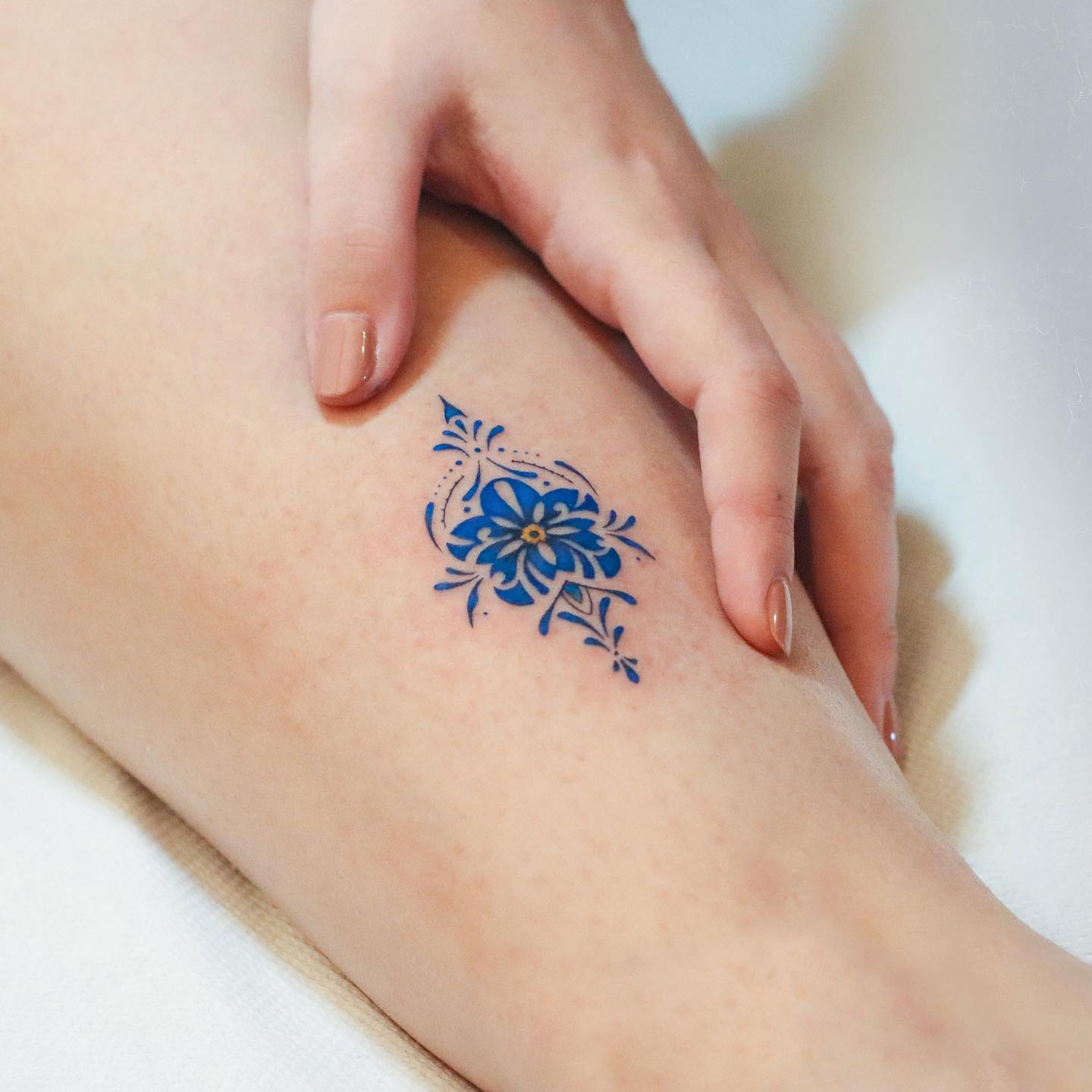 Blue ornamental flower tattoo on the leg