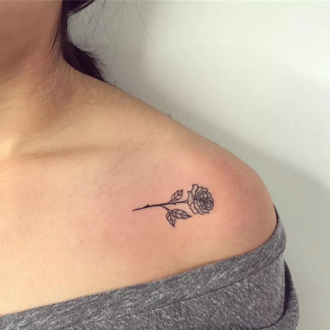 Person shows off the tiny tattoo on their shoulder, which is a horizontal rose