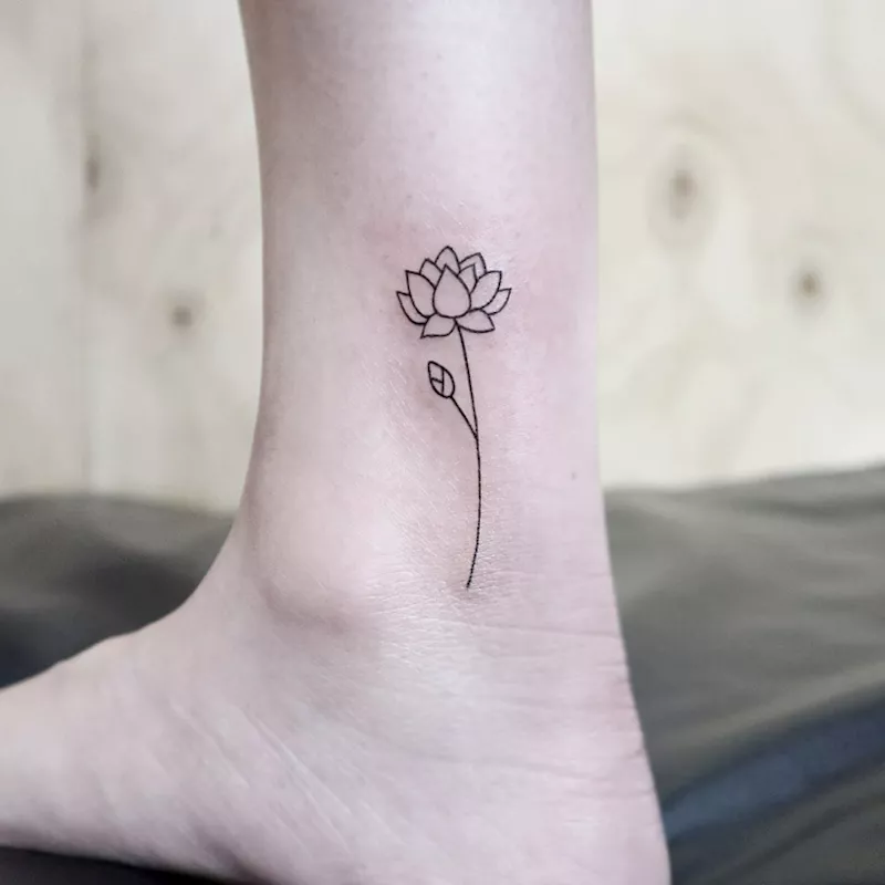 A stemmed lotus flower tattoo on an ankle