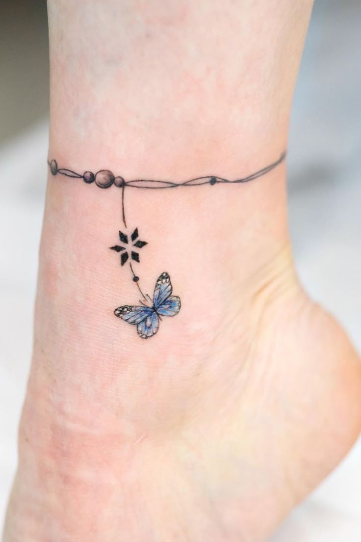 This may contain: a small tattoo on the ankle of a woman's foot with a blue butterfly
