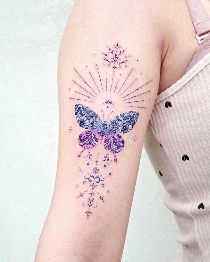 Colorful butterfly tattoo with intricate patterns on an arm.