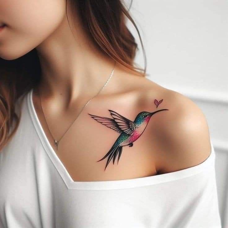 This may contain: a woman's chest with a hummingbird tattoo on her left shoulder and heart in the middle