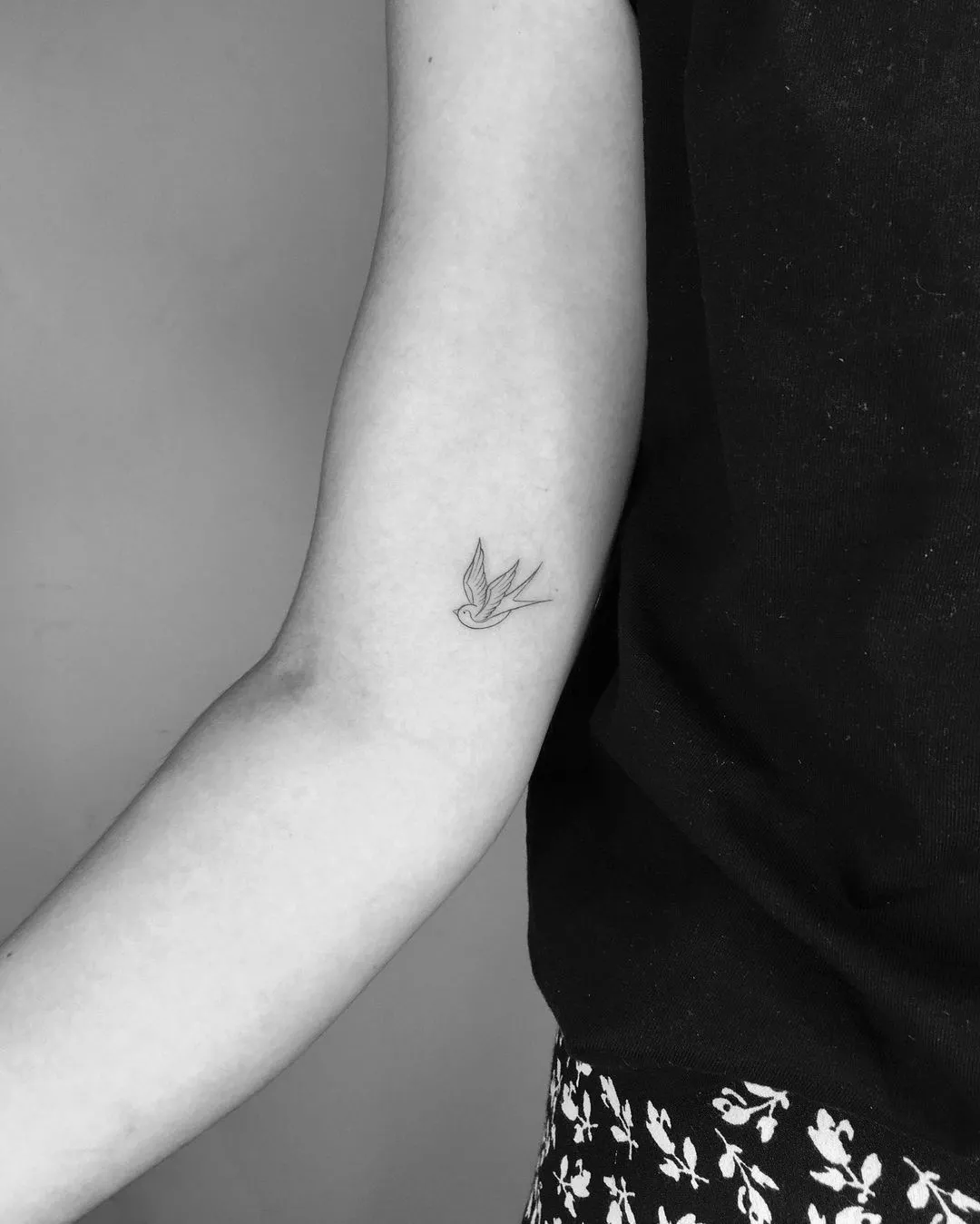 Person shows off a tiny tattoo of a bird on the inside of their arm