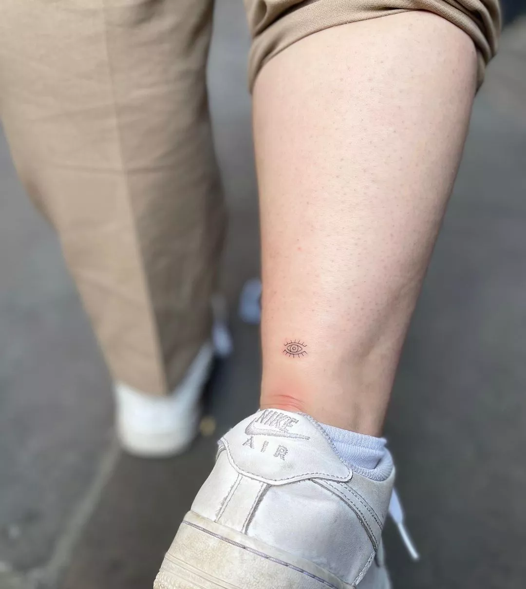 Person shows off the evil eye tiny tattoo right on top of their Achilles heel