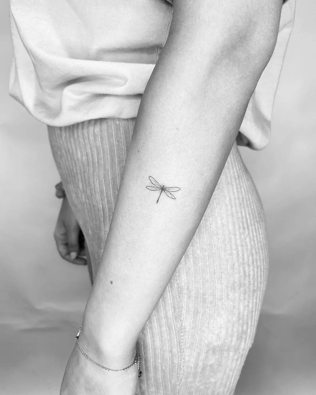 Person showing off the tiny tattoo of a dragonfly on the outside of their forearm